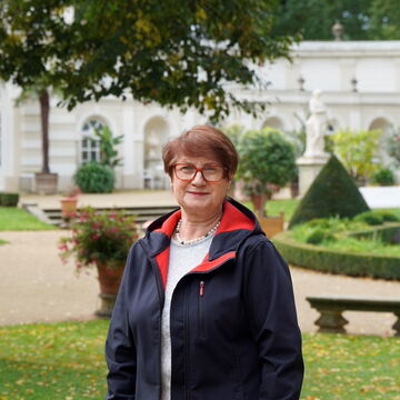Roswitha Karbaum mit dem Park und der Orangerie von Schloss Wiepersdorf im Hintergrund