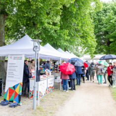 Various stalls at the Spring Festival 2025 with regional products, in front of them visitors with umbrellas
