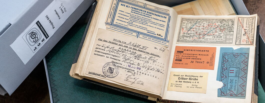 Ein aufgeklapptes Buch, das Eintrittskarten und anderes Archivmaterial zeigt