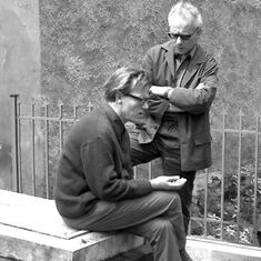 Black-and-white photograph showing Wolfgang Heise sitting on a gravestone belonging to the Arnim family, with Erwin Pracht standing behind him.