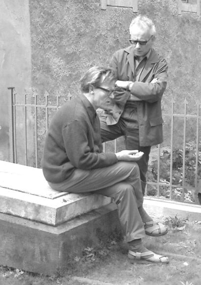 Schwarzweißfoto, auf dem Wolfgang Heise sitzend auf einem Grabstein der Familie Arnim zu sehen ist, dahinter steht Erwin Pracht.