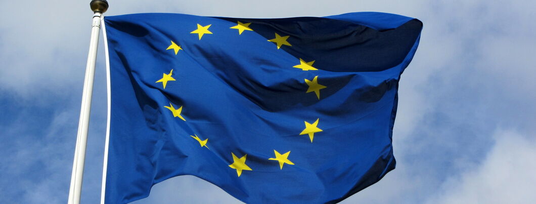 Die EU-Flagge weht im Wind, dahinter ein blauer Himmel