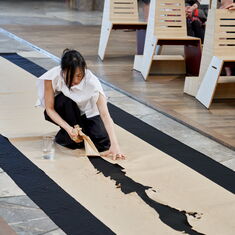 Performance artist Hyunju Oh tears a strip from the middle of a long piece of paper